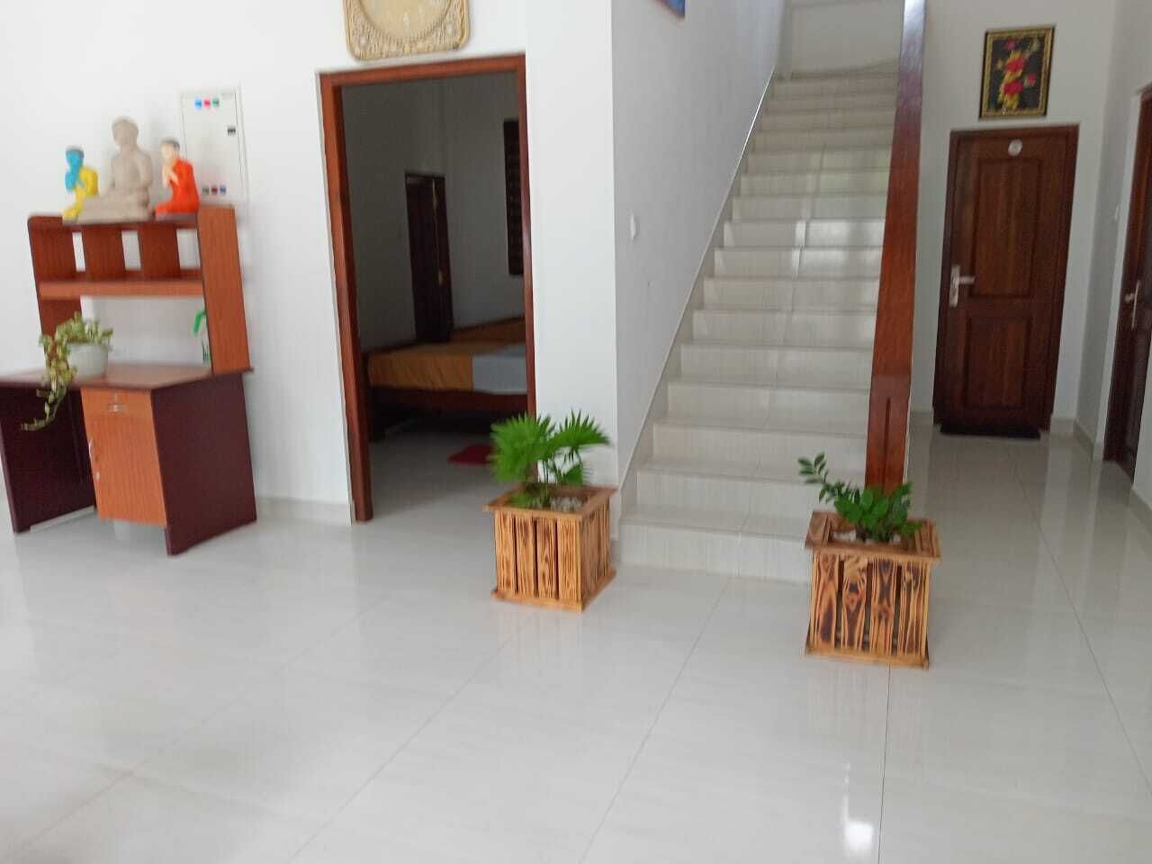 A clean, modern interior with a staircase, wooden furniture, and potted plants.