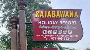 Schild für das Rajabawana Holiday Resort mit Symbolen für Annehmlichkeiten, einer Kontaktnummer und einem separaten Schild mit Zimmerinformationen.