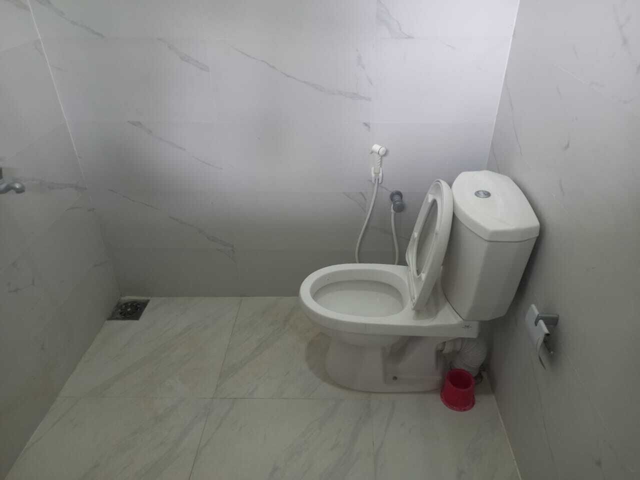 Une petite salle de bain moderne avec des toilettes, une douche et un seau rouge.