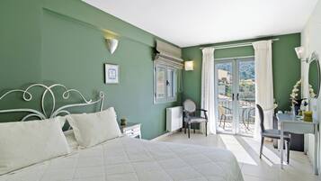 Ein Schlafzimmer mit einem Bett, einem Schreibtisch und einem Stuhl. Ein Fenster mit Vorhängen bietet einen Ausblick ins Freie.