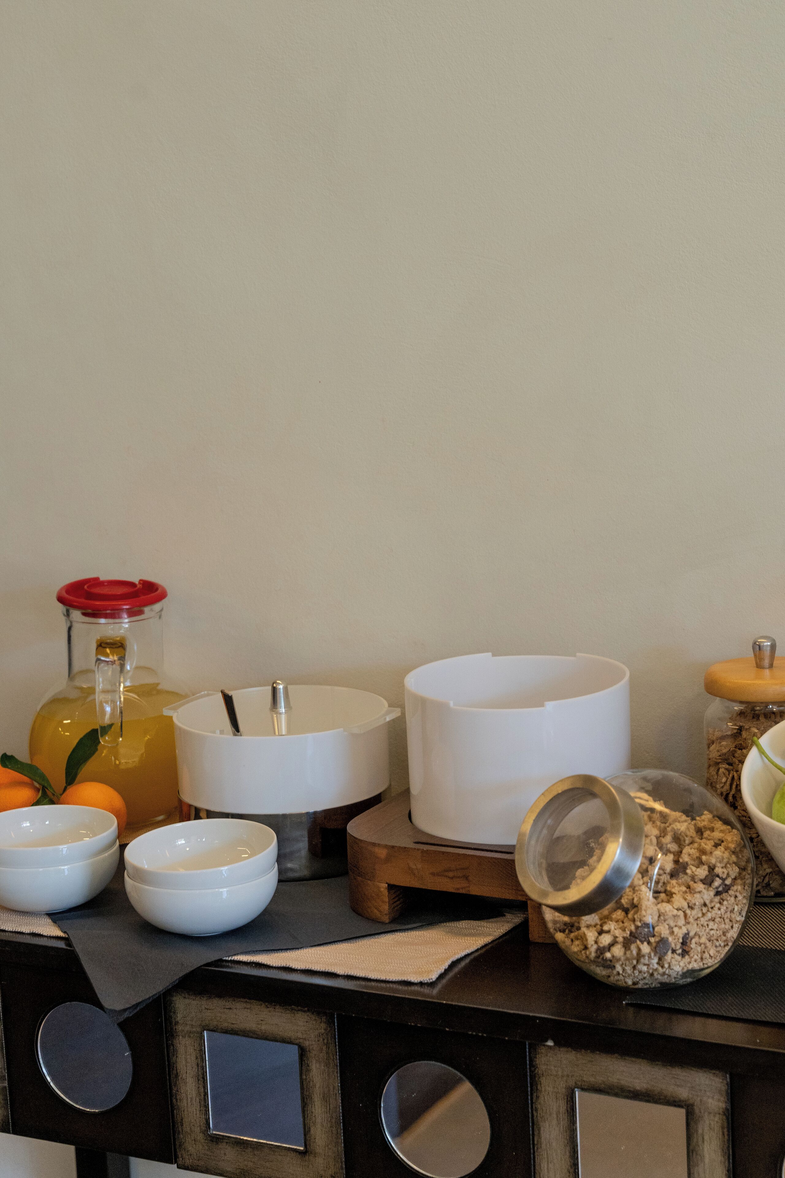 A kitchen counter with various bowls, a glass jar, and a bottle.