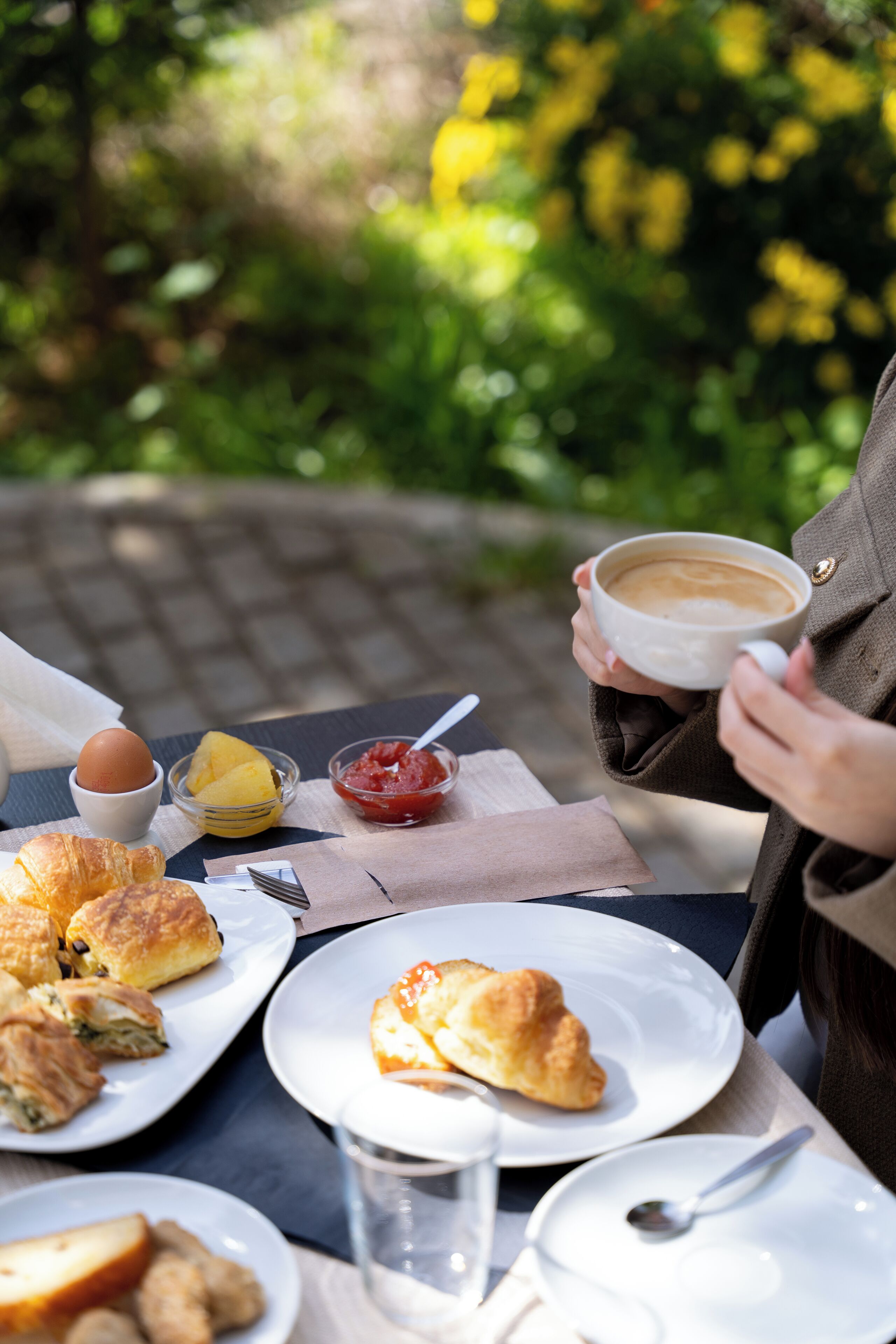 Une table avec des aliments pour le petit-déjeuner, notamment des croissants, une tasse de café et un verre d’eau.