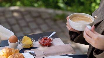 Une table avec des aliments pour le petit-déjeuner, notamment des croissants, une tasse de café et un verre d’eau.