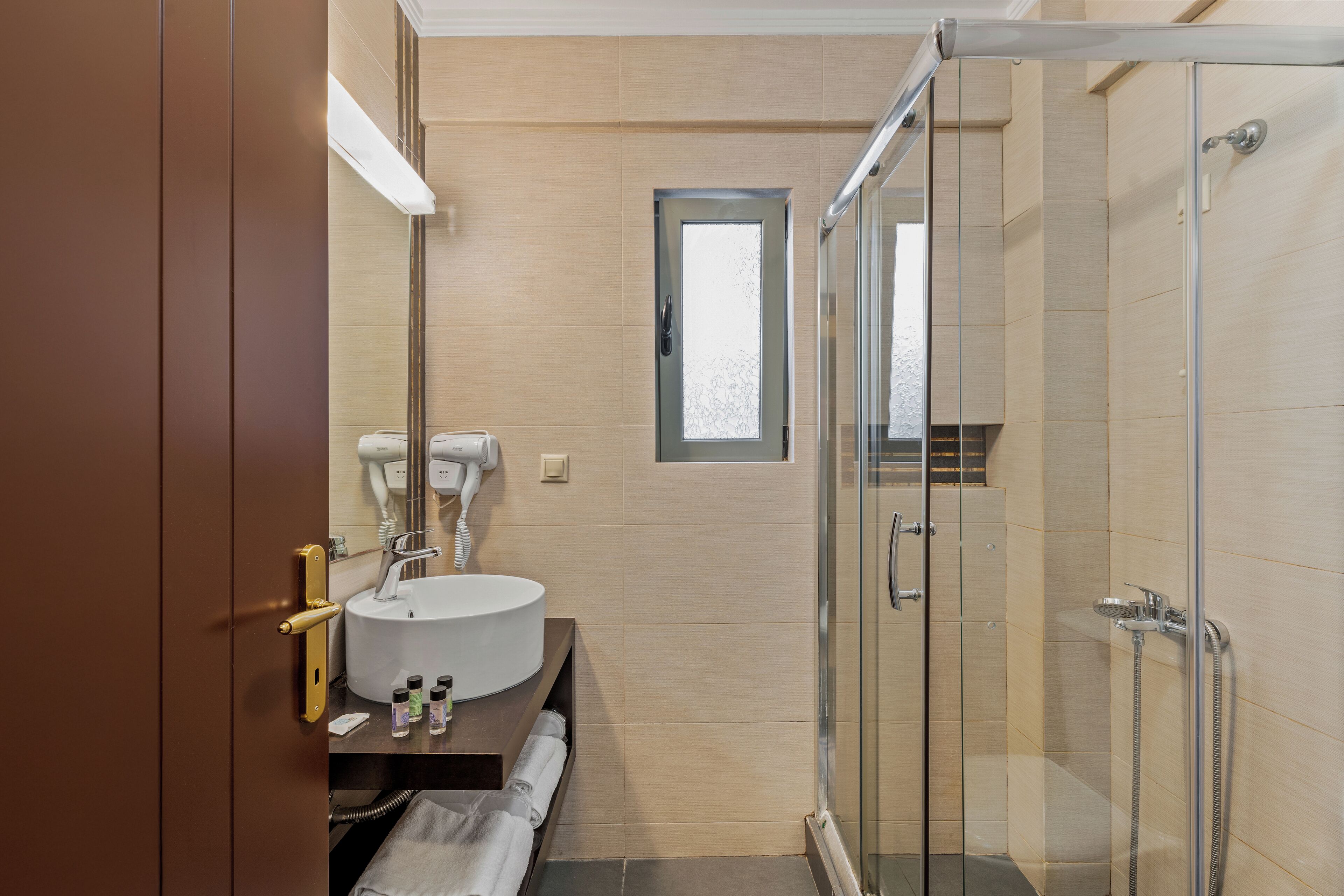 A modern bathroom with a glass shower enclosure, a sink with a mirror, and a towel rack.