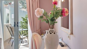 Una stanza con un balcone, un vaso con fiori, una sedia e un tavolo.