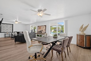 A modern dining area with a table, chairs, and a ceiling fan.