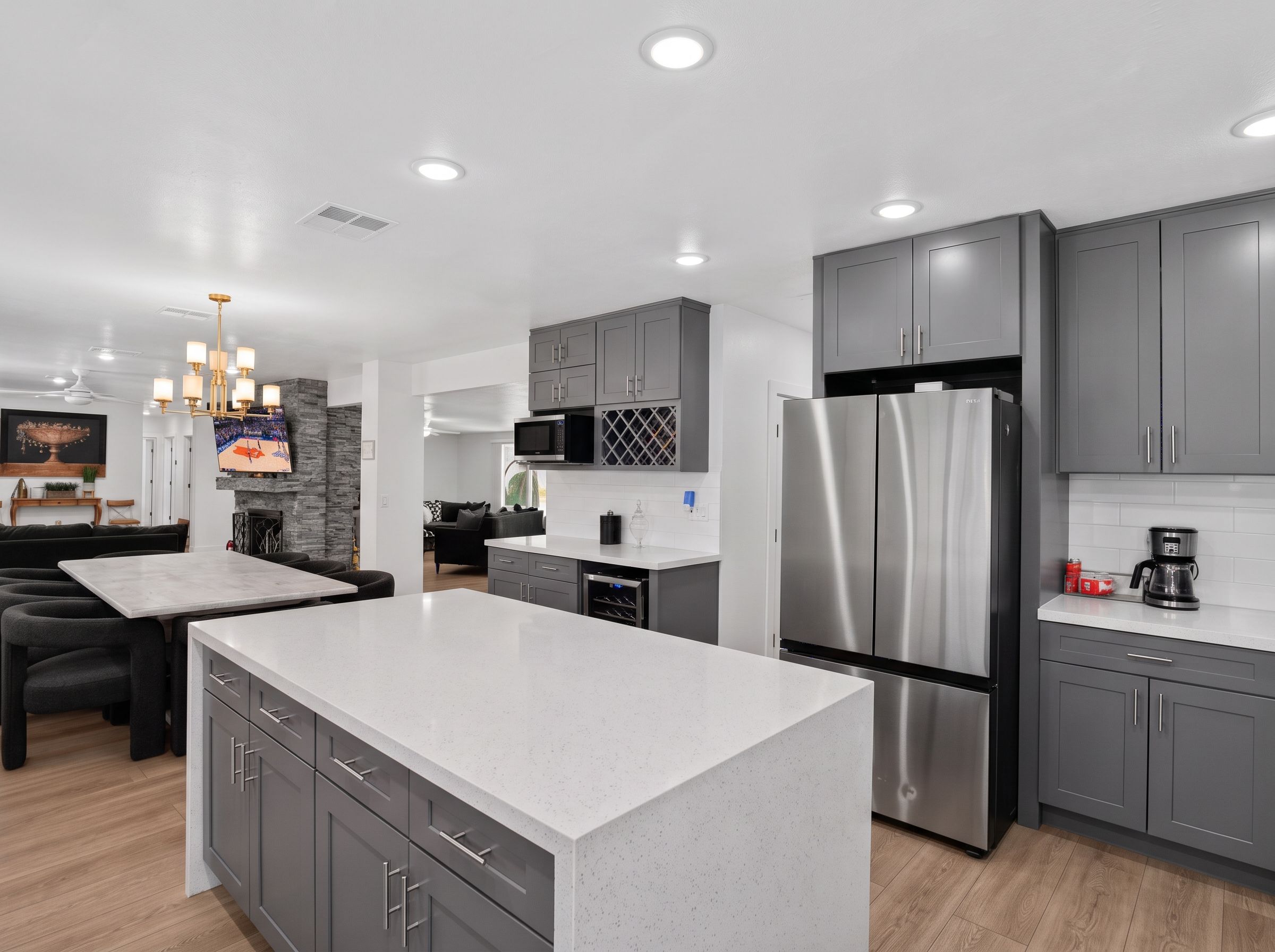A modern kitchen with grey cabinets, a stainless steel refrigerator, and a microwave.
