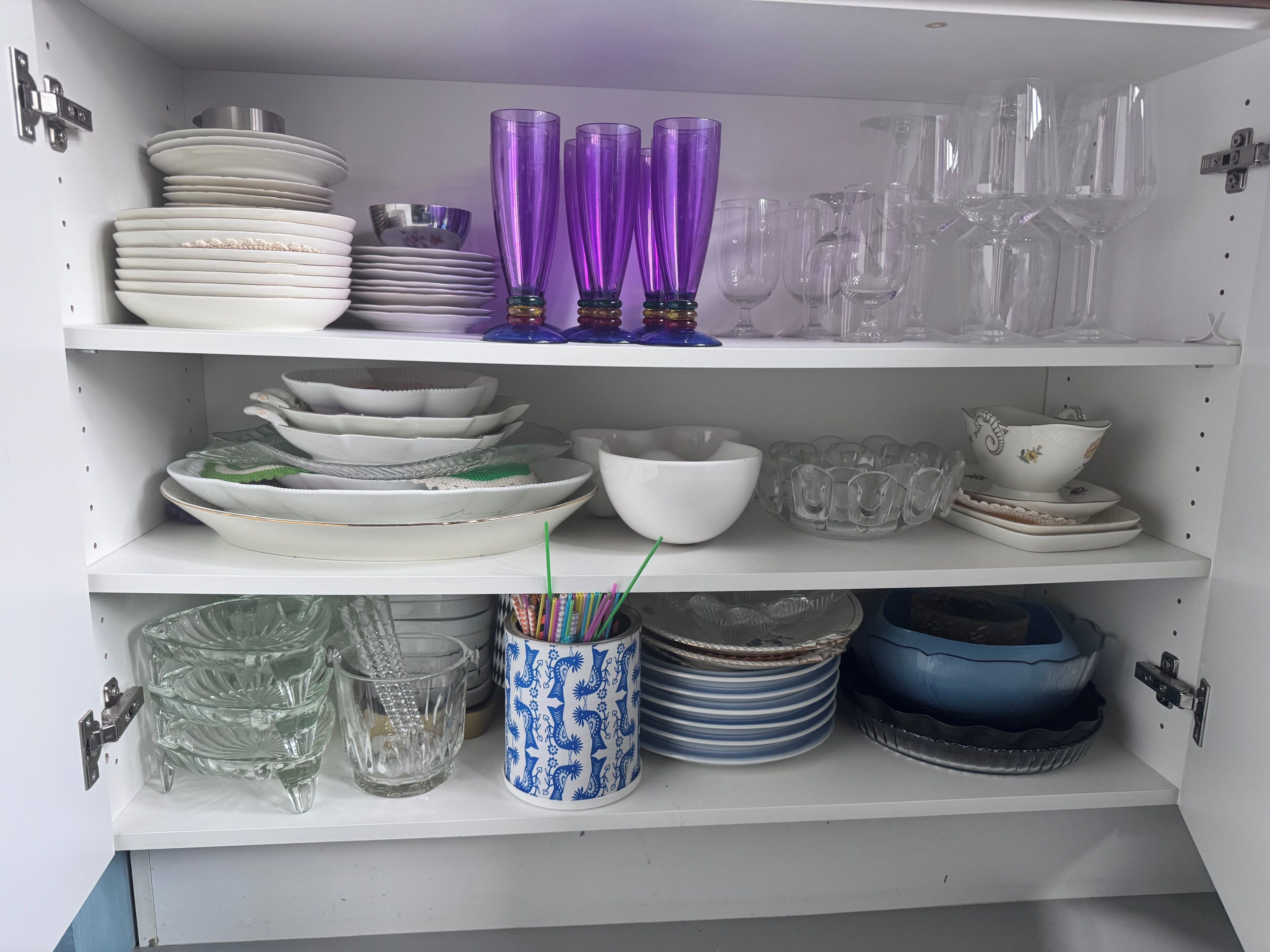 Un meuble de cuisine contenant divers plats et articles en verre.