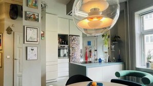 A modern kitchen with a central island, pendant lighting, and a dining area with a round table. - Spacious apartment for a family of 4 with easy access to metro, grocery, parks (København)