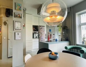 Una cocina moderna con una isla central, iluminación colgante y un comedor con una mesa redonda.