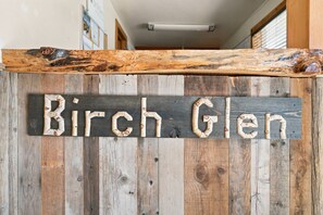A rustic wooden sign with the text 'Birch Glen' against a backdrop of vertical wooden planks.