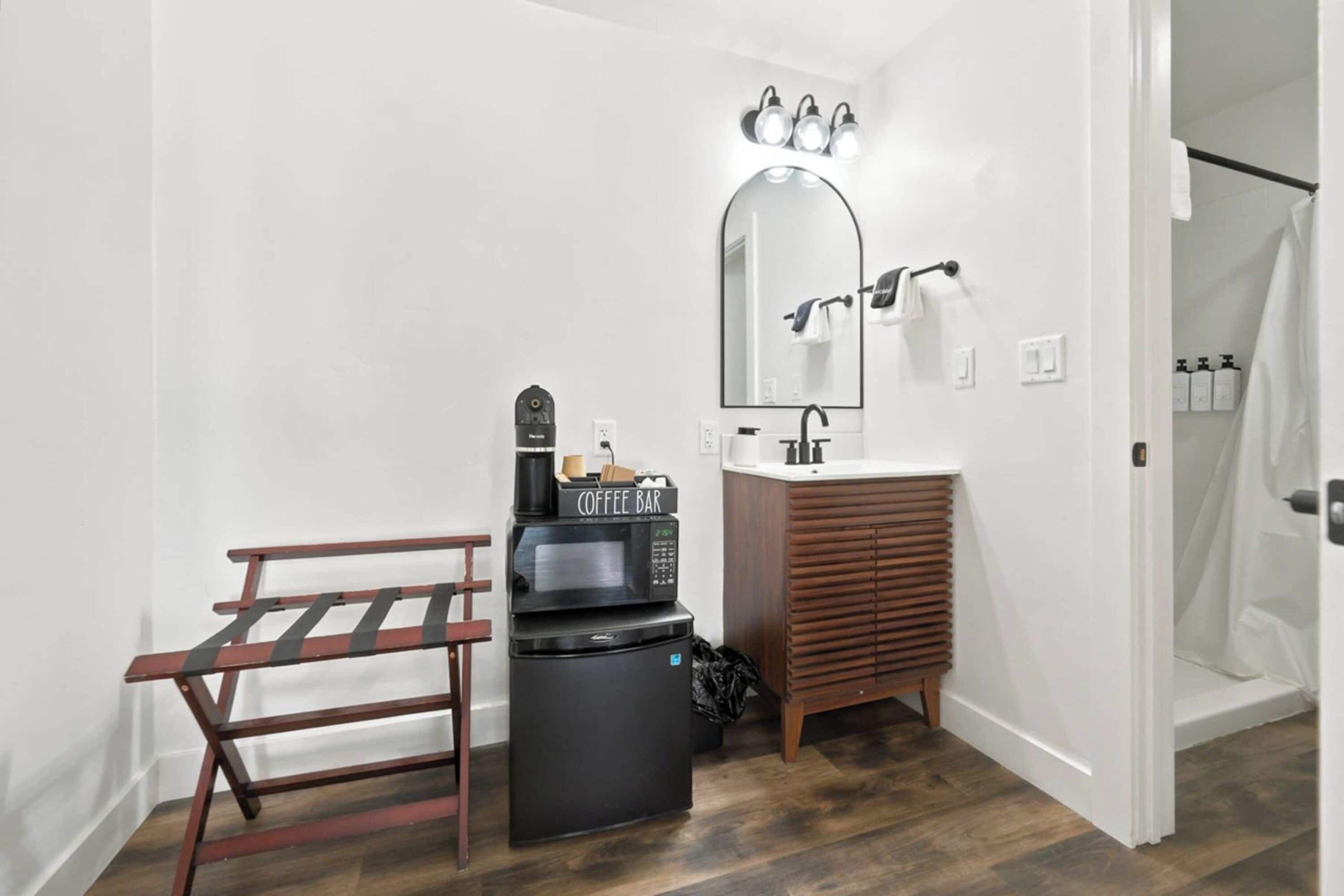 A compact bathroom with a sink, mirror, and a coffee machine.
