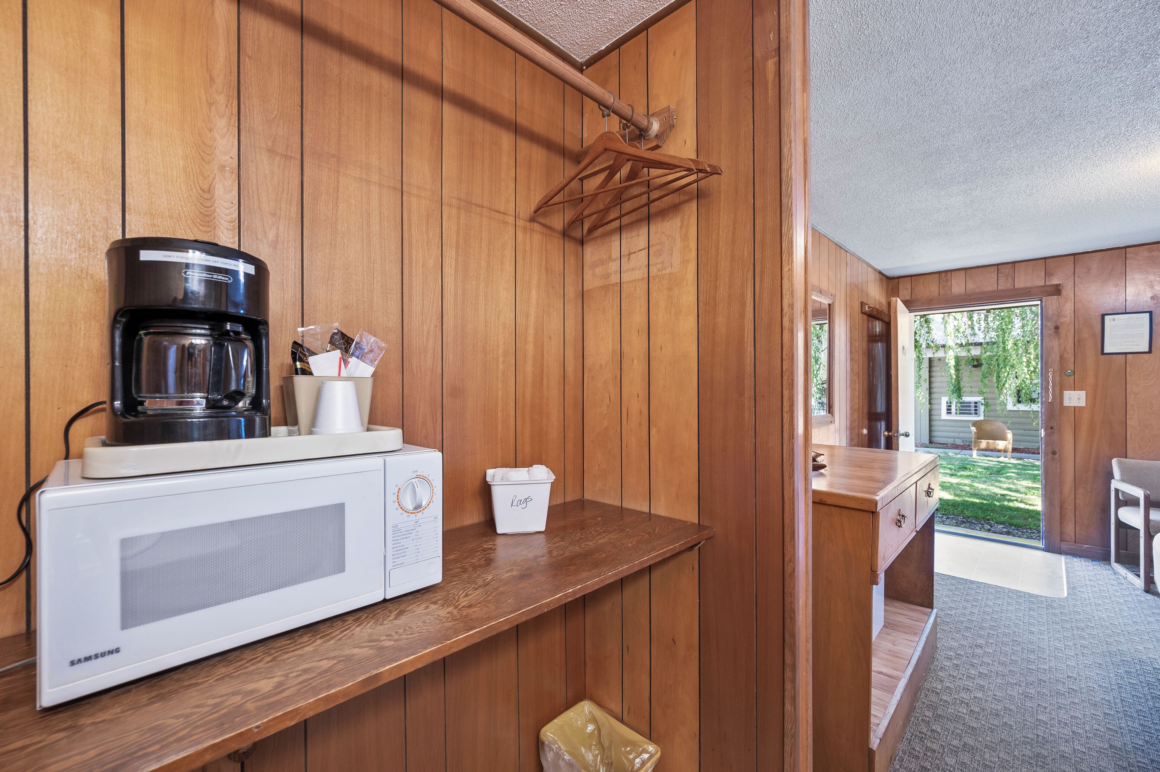 Una cocina equipada con microondas, cafetera y un perchero.