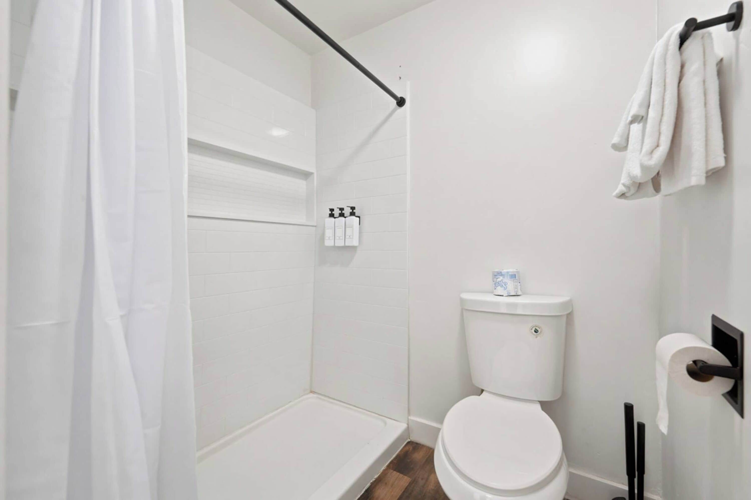 A modern bathroom with a shower, toilet, and towel rack.