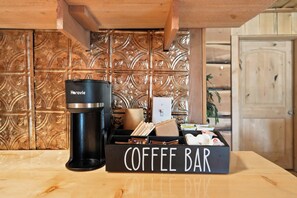 Une machine à café, une enseigne pour un bar à café et un meuble en bois doté d’un panneau arrière décoratif.