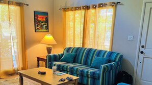 Un salon avec un canapé à rayures, un fauteuil bleu, une table basse en bois et un tapis.