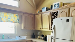 Une cuisine avec des meubles en bois, un réfrigérateur blanc et une fenêtre donnant sur un beau paysage.