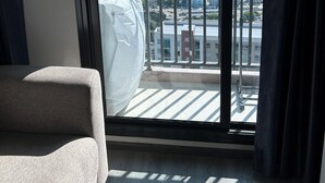 Ett rum med ett stort fönster med utsikt över stadsbilden, en soffa och en luftkonditioneringsanläggning som är monterad i taket.