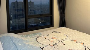 Ett hotellrum med ett stort fönster som erbjuder utsikt över staden i skymningen.