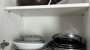 Ett köksskåp med hyllor för förvaring av köksredskap och porslin.