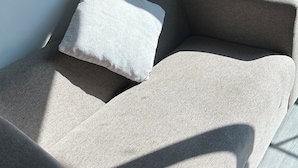 En hörna i ett rum med en beige soffa och en vit kudde.