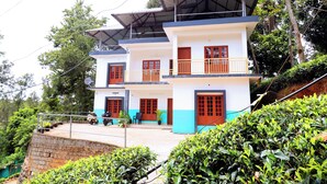 A multi-story building with a balcony, a satellite dish, and a staircase leading up to the entrance. - Tea Haze Cottage Munnar (Anachal)