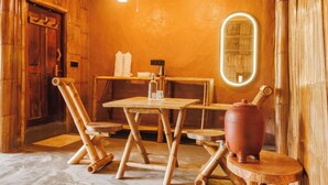A rustic wooden interior with a wooden table, chairs, a coffee machine, and a large vase. - KaatiKaadu (Sakleshpur)
