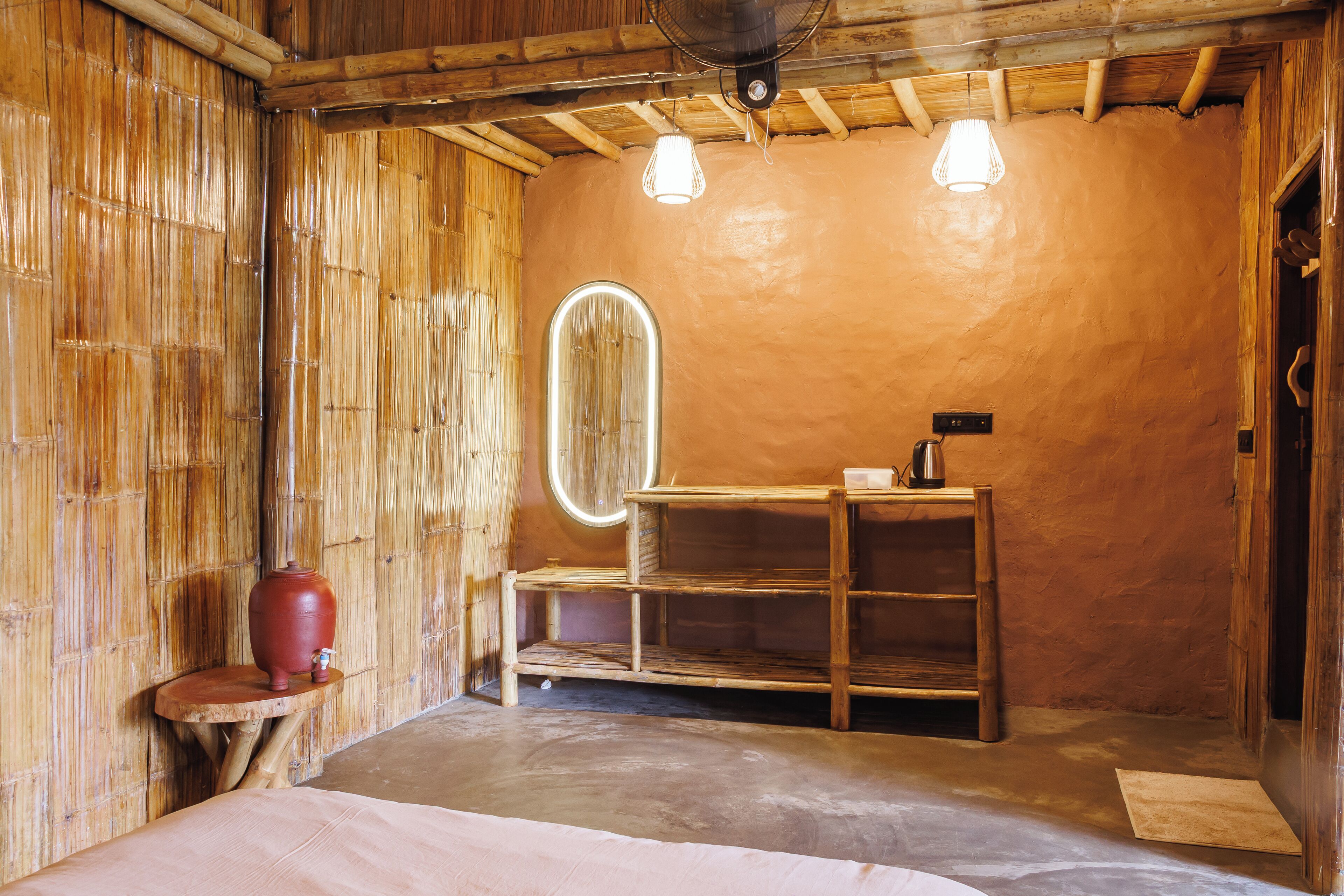 Una habitación con paredes de bambú, un estante de madera, un espejo y una cama.
