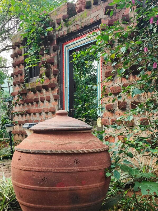 A rustic brick structure with a large terracotta pot in front.