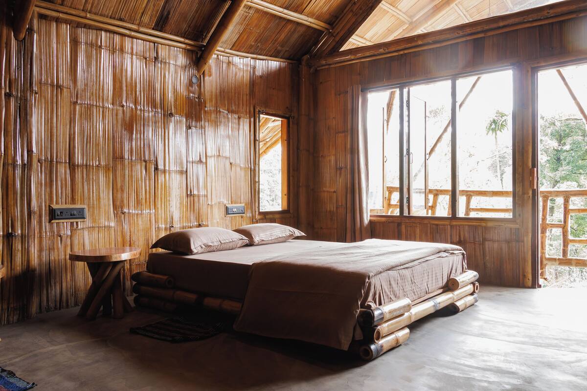 A room with a large bed, wooden walls, and a window with a view of greenery.