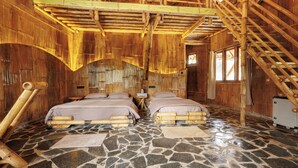 A room with two beds, a stone floor, and a bamboo ceiling. - KaatiKaadu (Sakleshpur)