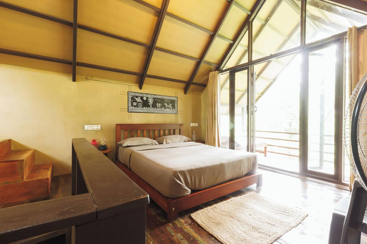 A bedroom with a wooden bed, a desk, and a large window with curtains.