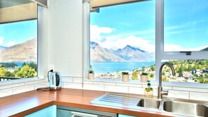 A kitchen with a view of mountains and a lake.