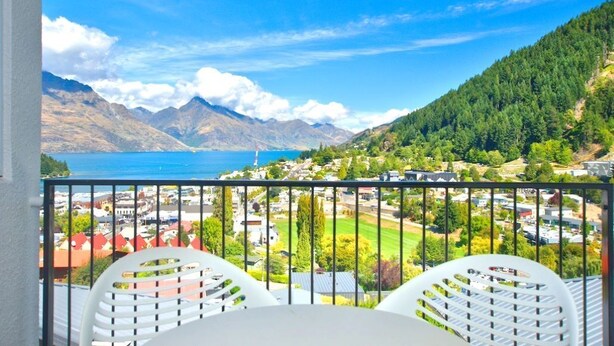 A balcony with a view of a coastal town, mountains, and a body of water.