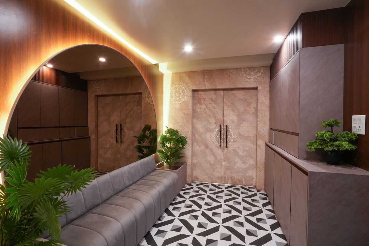 A modern hallway with a geometric patterned floor, a grey sofa, and wooden cabinets.