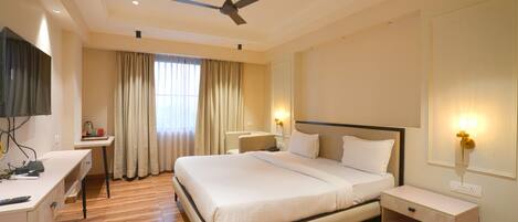 Habitación de hotel con cama, escritorio, silla y televisor.