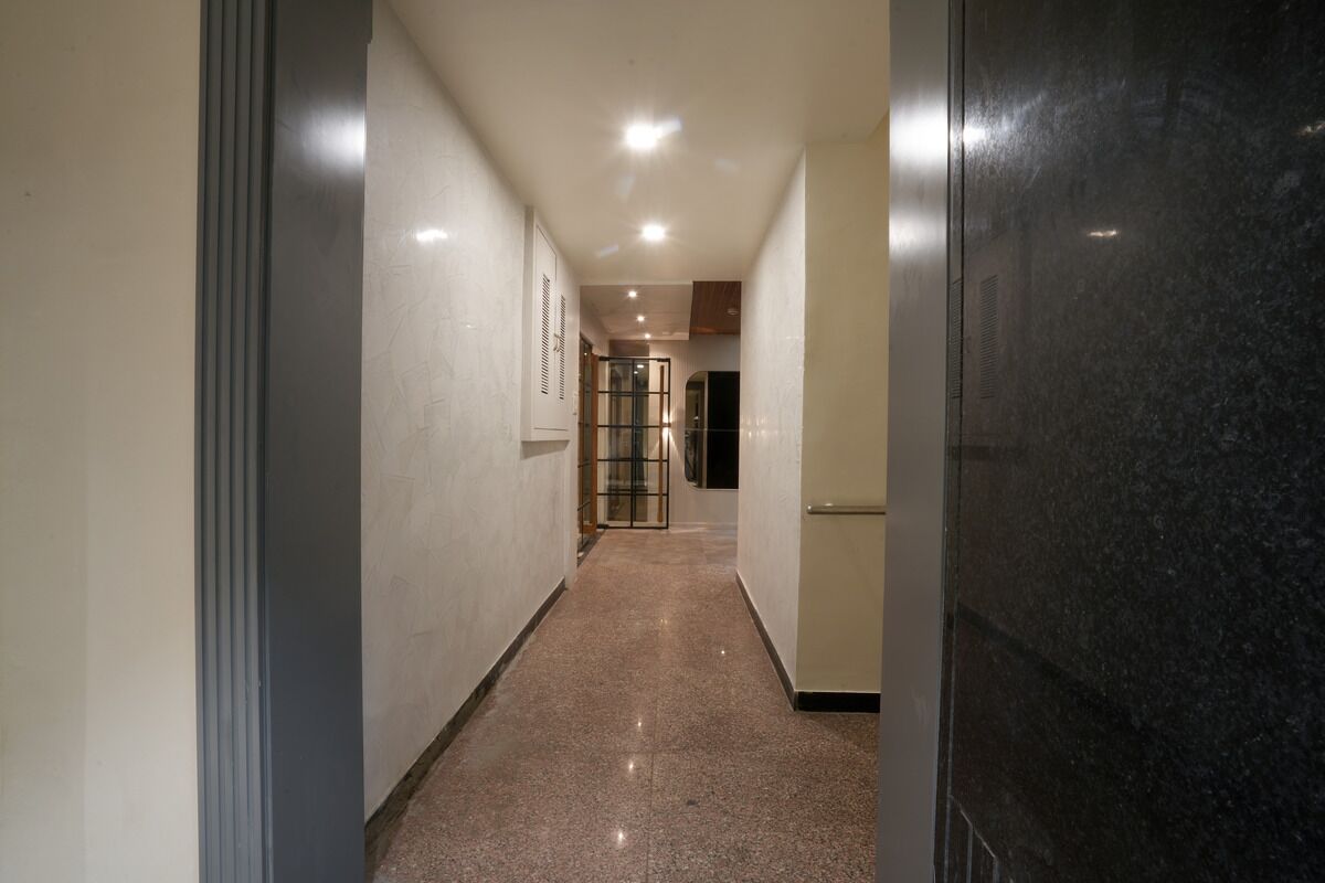A hallway with a polished floor, a door on the right, and a door at the end.