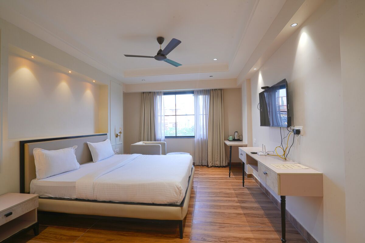 A hotel room with a large bed, a desk, a ceiling fan, and a TV mounted on the wall.