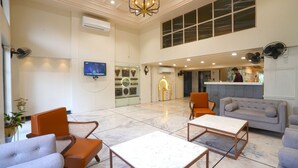 A spacious lobby with a high ceiling, a chandelier, seating areas, and a reception desk. - Hotel Square 36 (Kota)