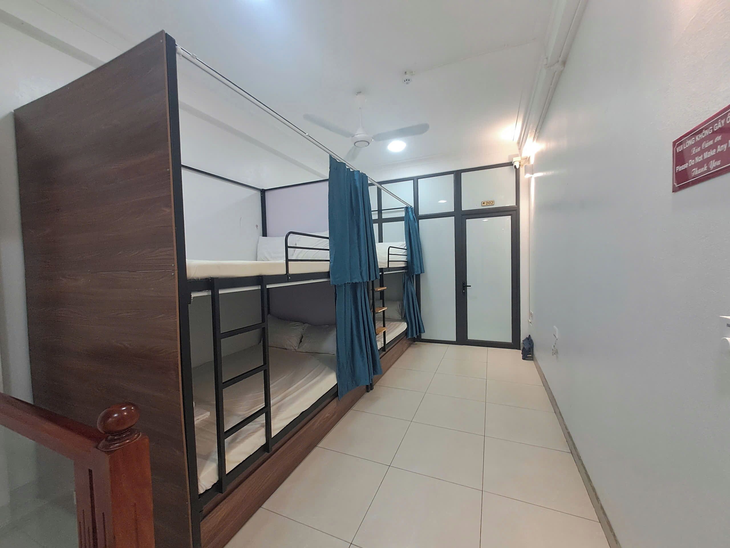 A room with bunk beds, a ceiling fan, and a door with a sign.
