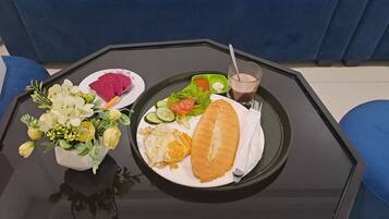 A dining table with a plate of food, a glass of beverage, and a vase of flowers.