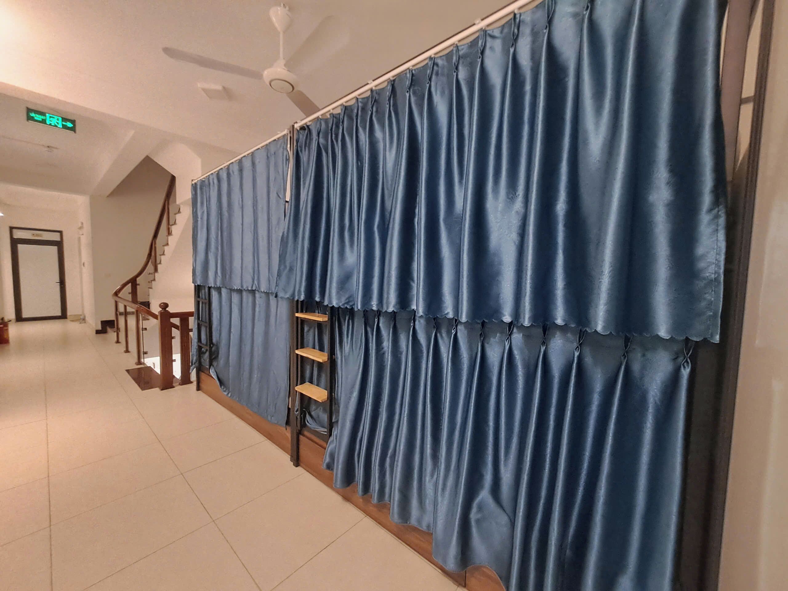 A hallway with a staircase, a ceiling fan, and a blue curtain.