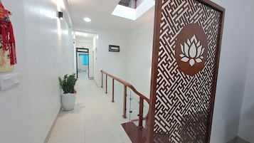 Um corredor com um painel de madeira decorativo, uma planta em vaso e uma escada com corrimão de madeira.