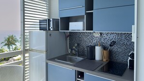 Una cocina moderna con microondas integrado, un lavamanos y una cafetera.