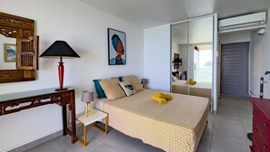 Un dormitorio con cama, mesita de noche, lámpara y espejo.