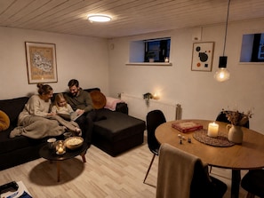 A cozy living room with a sofa, a coffee table, a dining table with chairs, and a fireplace.