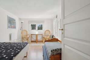 A room with a bed, a chair, a table, a window, and a door.