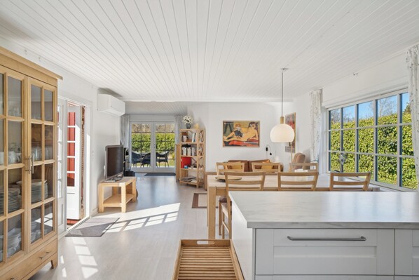 A spacious kitchen with a large island, wooden cabinets, and a view of greenery outside.