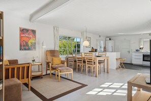 A modern living room with a dining area, kitchen, and a large window.