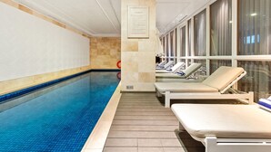 Una piscina con sillas de descanso y una pared de azulejos.